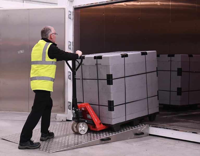 Man in yellow vest loading a container with a pallet jack