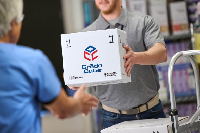 Two men handing over a Crēdo Cube box